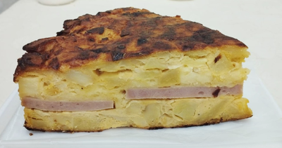 Porción de tortilla de papa rellena con jamón y queso