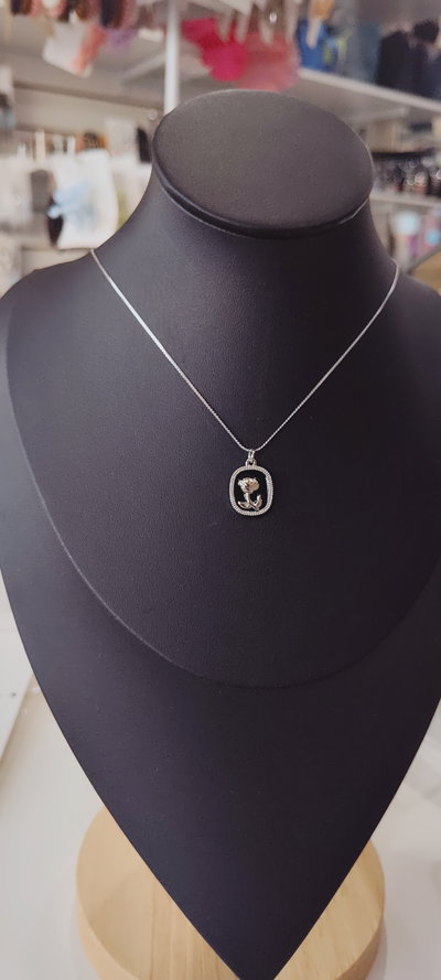 Cadena AQ con dije flor sobre fondo negro