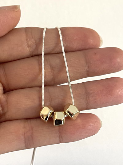 Collar combinado con dijes dorados y cadena plateada