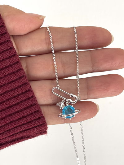 Collar con dije de broche y Saturno con cubic celeste .