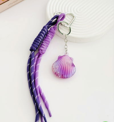 Bag Charms llavero ostra tono Lilas tornasol y cordones al tono 