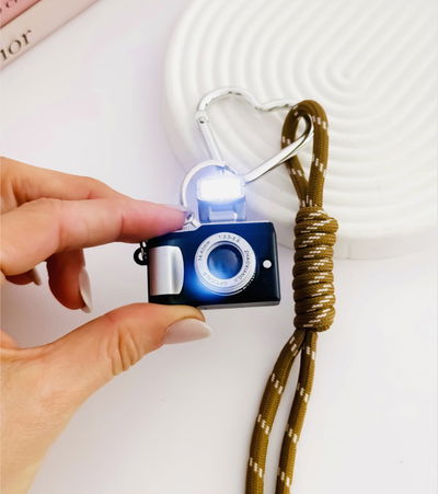 Bag Charms cámara fotográfica negra (con luz ) y cordon moca 